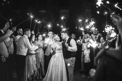 Black and white photo of bride and groom with sparklers.