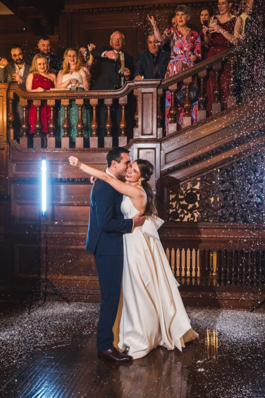 A bride and groom kissing in front of a crowd of people.