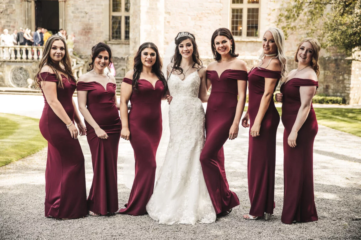 A group of bridesmaids posing for a picture in burgundy dresses.