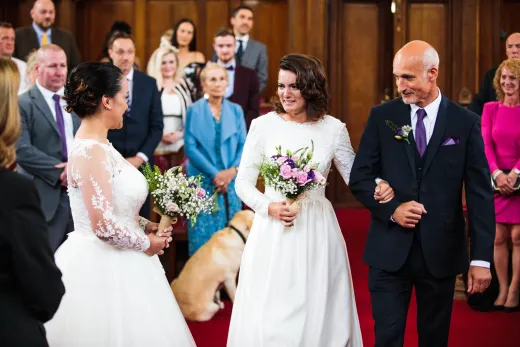 A bride and groom walking down the aisle with their dog.
