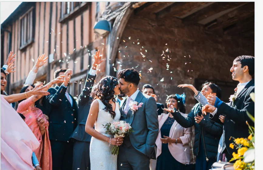 A bride and groom kissing in front of confetti.