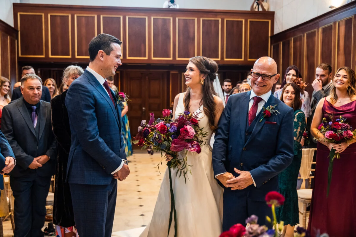 A bride and groom smiling at each other during their wedding ceremony.