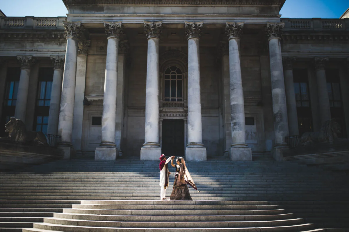 An indian couple standing on steps in front of a building.