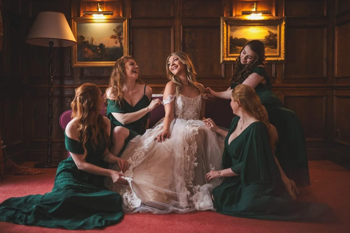 A bride and her bridesmaids sitting on a couch in a room.