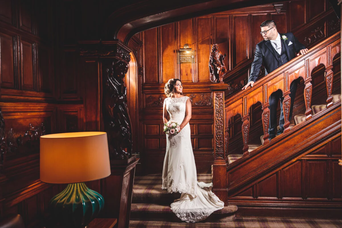 A bride and groom standing on a wooden staircase.