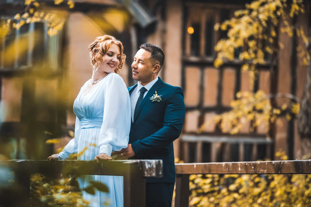 A bride and groom posing for a photo in front of an old building.