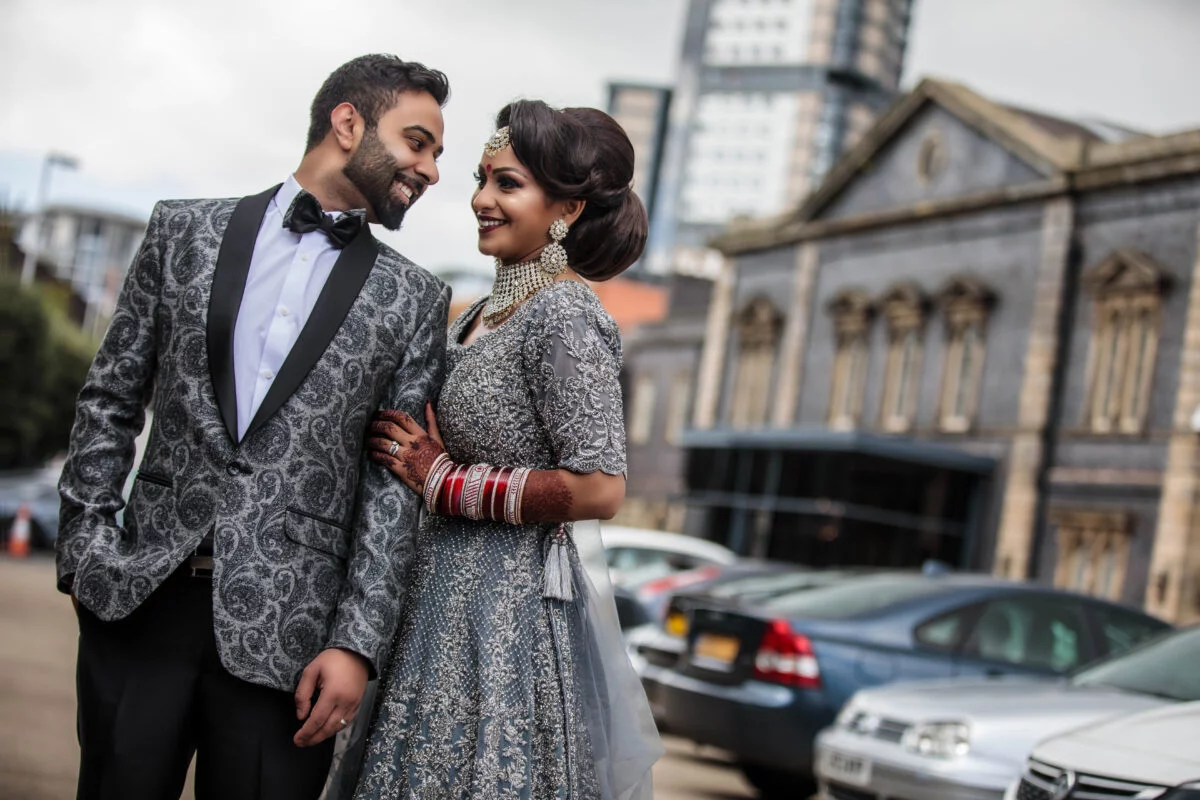 An indian bride and groom posing in front of a building.