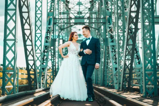 Bride and groom posing on a bridge.