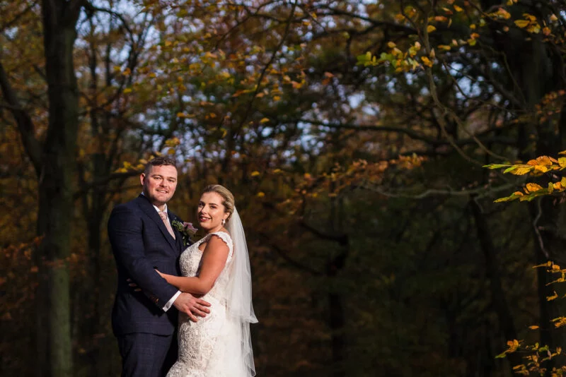 A bride and groom posing for a photo in the woods.