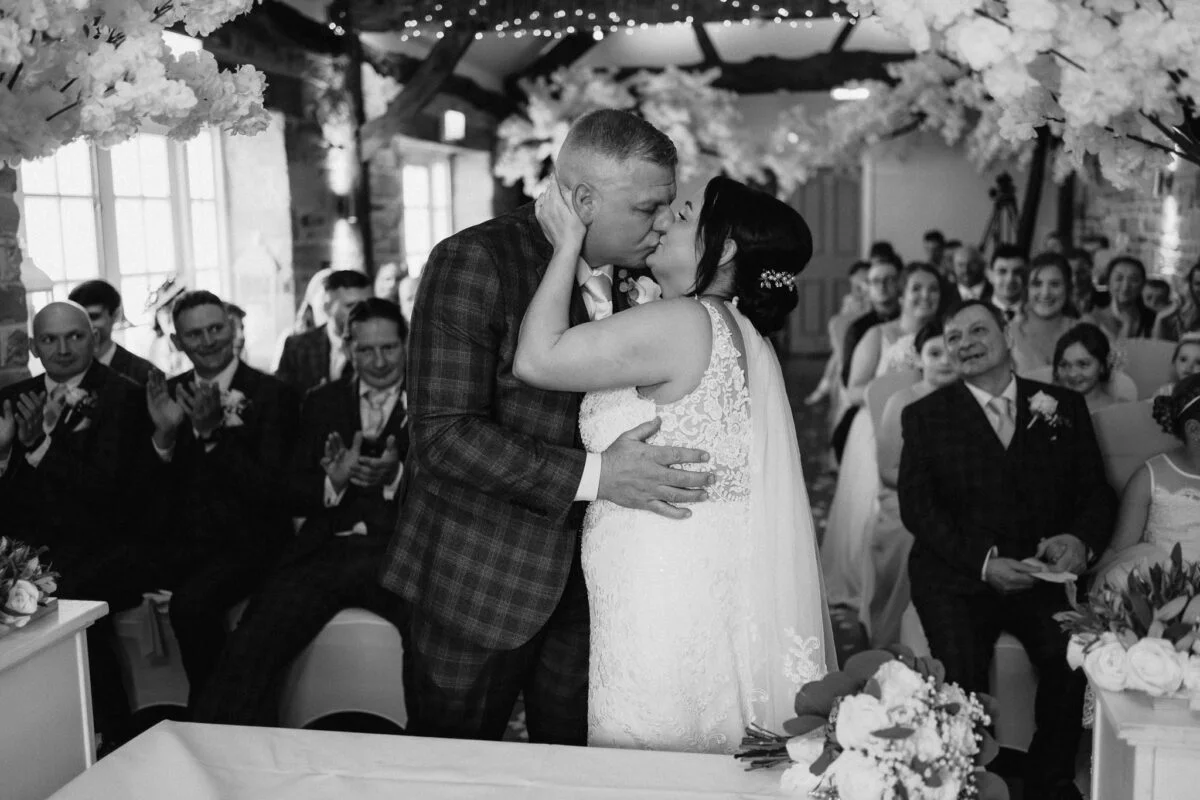 A bride and groom kiss during their wedding ceremony.