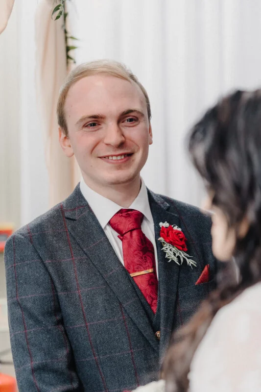 A bride and groom smiling at each other during a wedding ceremony.