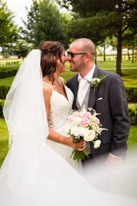 A bride and groom kissing in the grass.