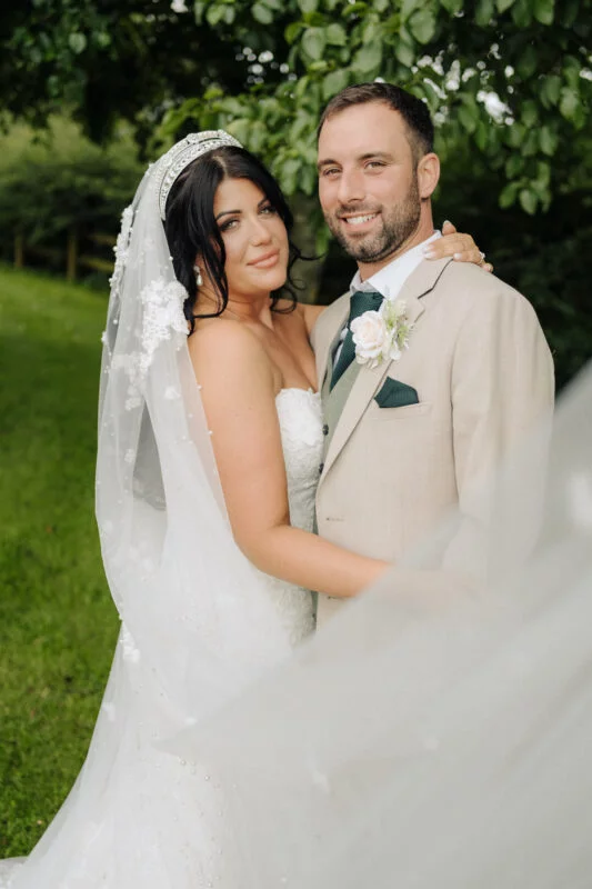 A bride and groom posing for a photo in a field.