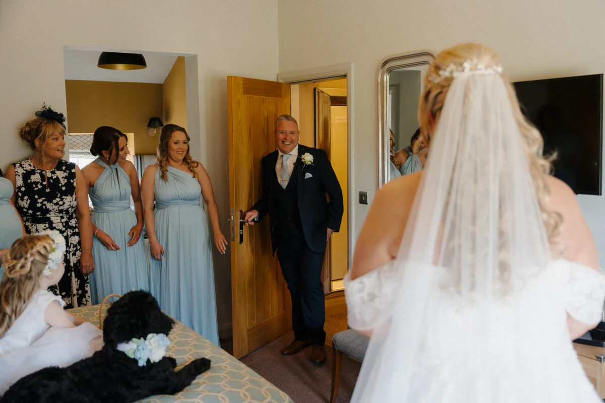 A bride and her bridesmaids are standing in a room with a dog.