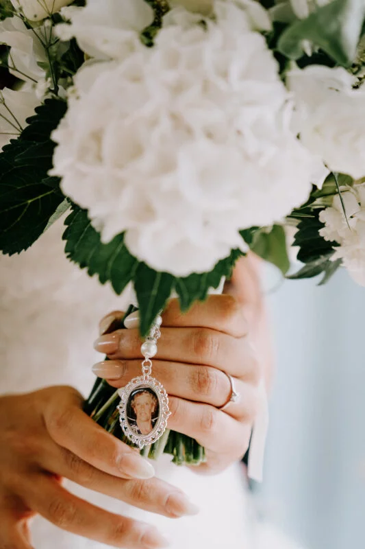 A bride holds a photo of her mother in her bouquet.