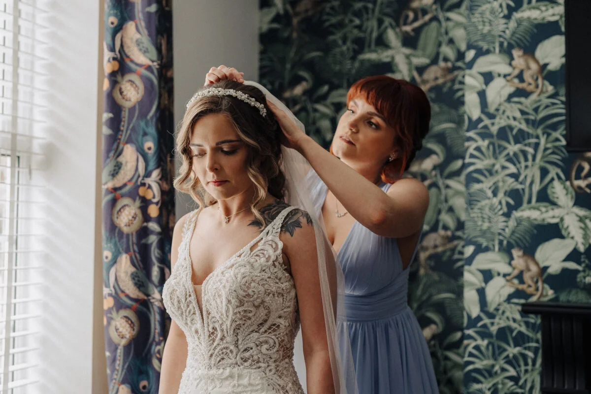 A bride getting her hair done by a bridesmaid.