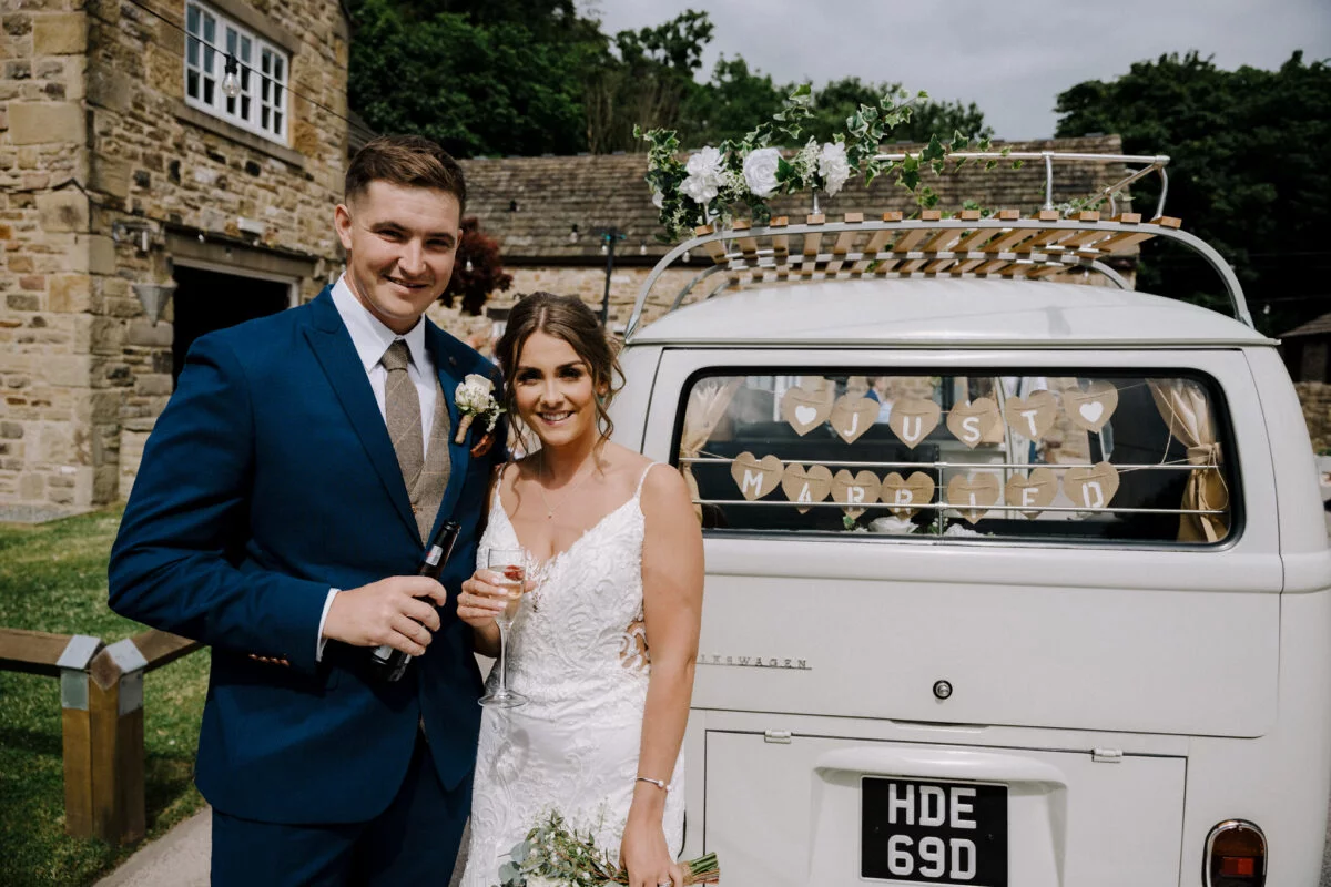A bride and groom standing next to a vw camper van.
