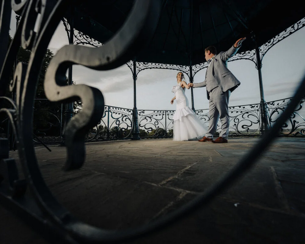 A bride and groom standing in front of a gazebo.