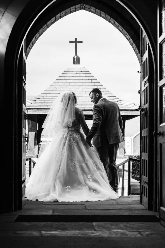 A bride and groom standing in the doorway of a church.