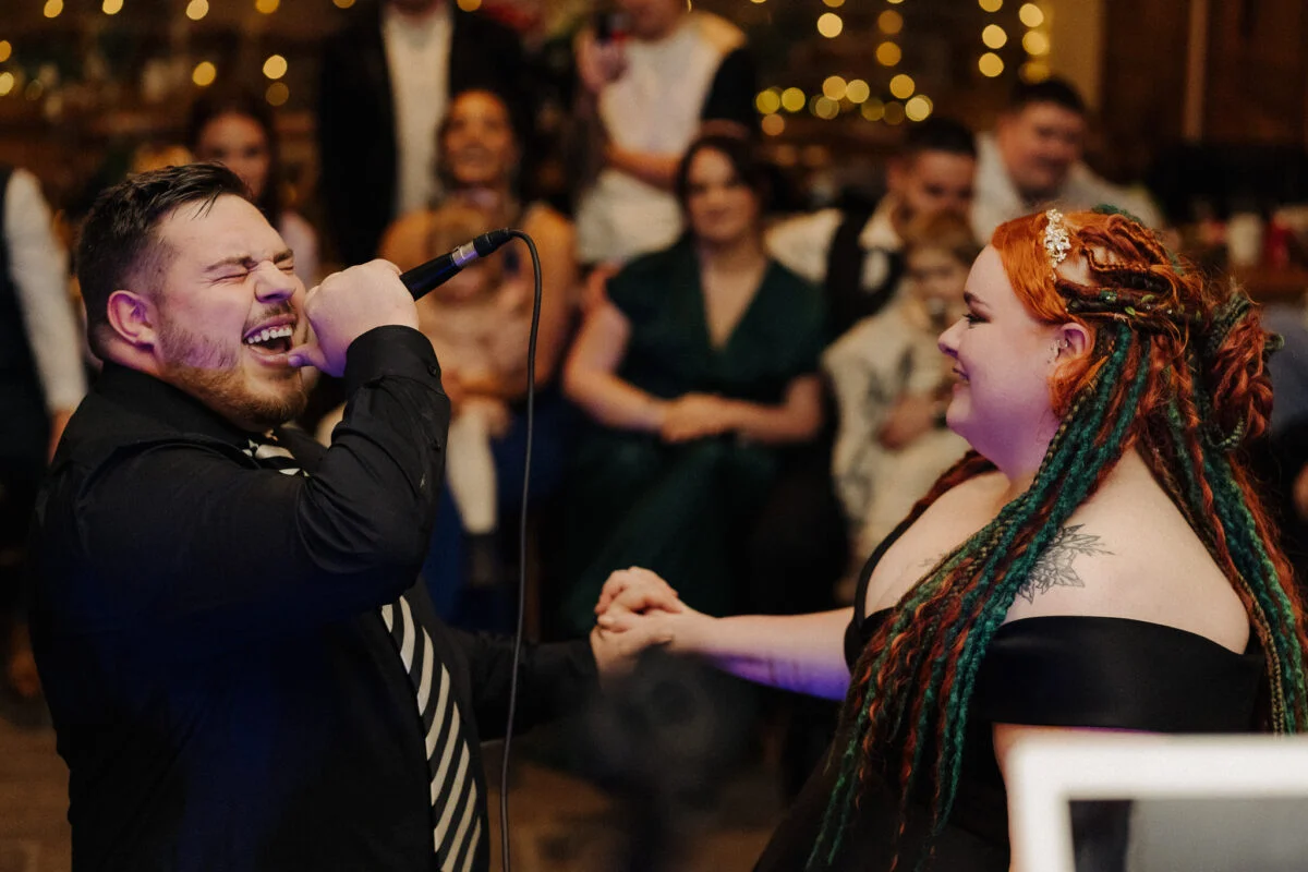 A man and woman singing into a microphone at a wedding reception.