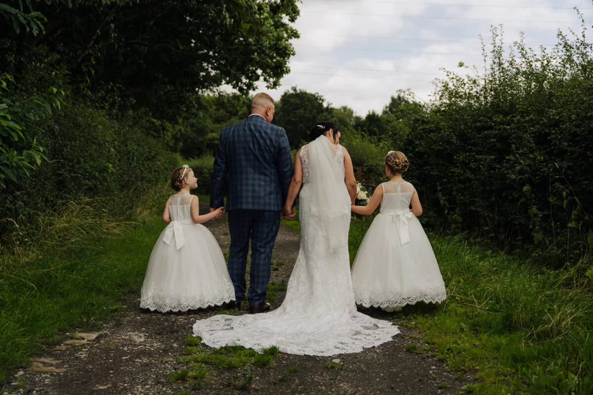 A bride and bridesmaids walking down a path.