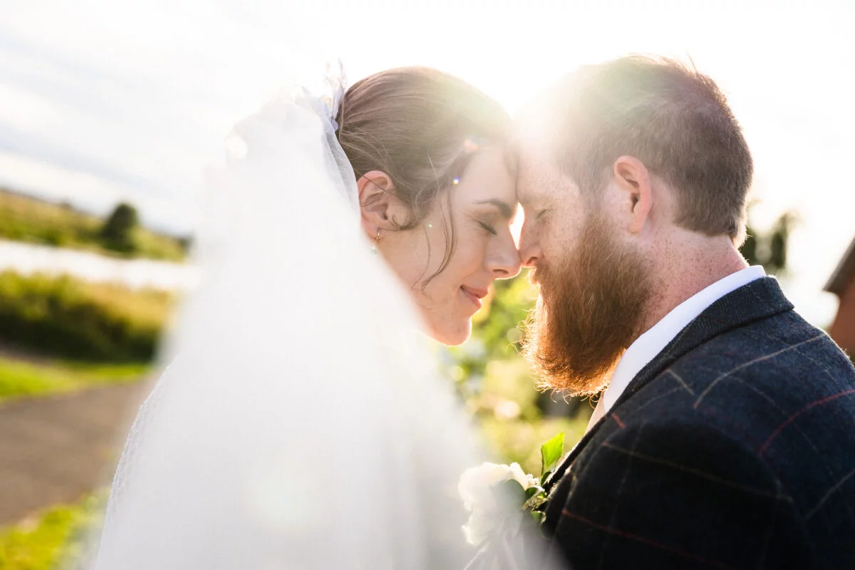 A bride and groom looking at each other in the sun.