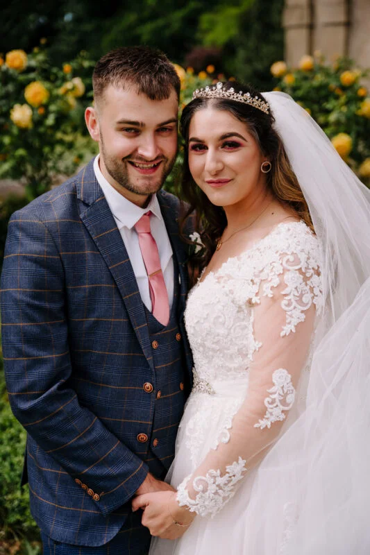 A bride and groom posing for a photo in a garden.