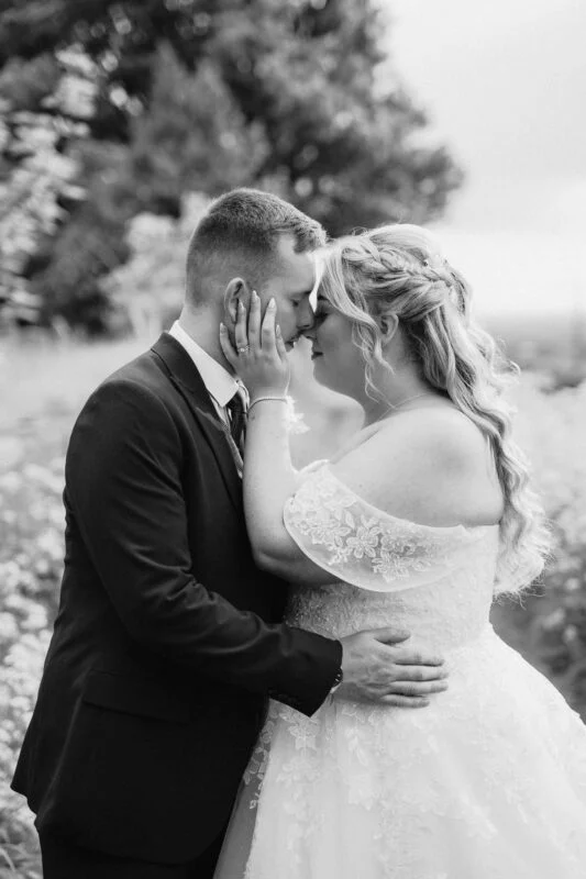 A bride and groom kissing in a field.