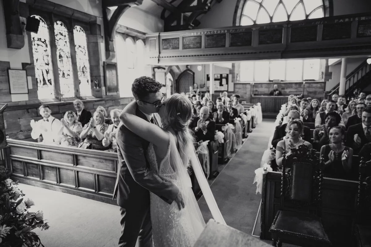 A bride and groom kissing in a church.