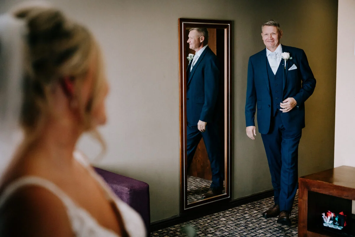 A bride and groom standing in front of a mirror.
