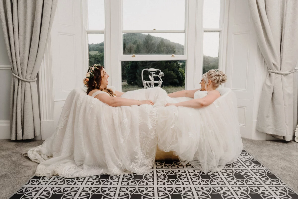 Two brides sitting in a bathtub in a room.