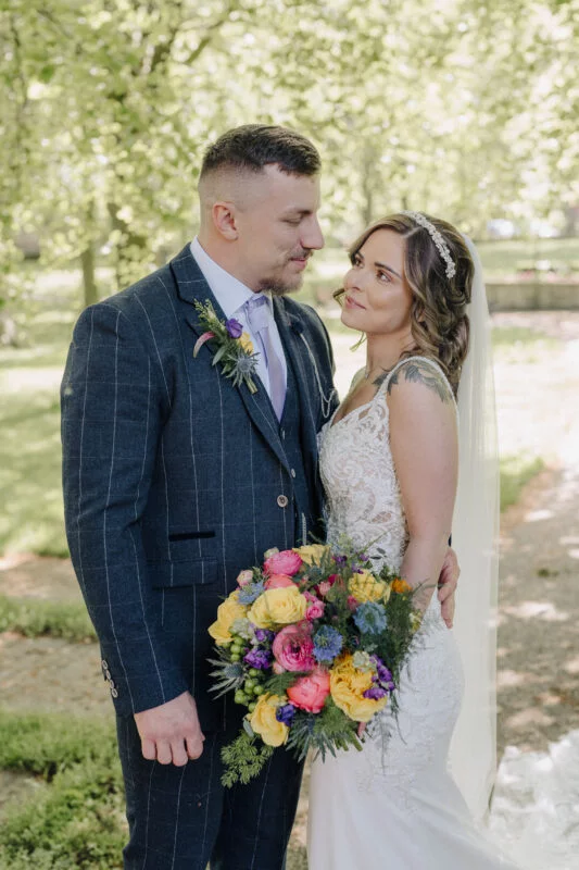 A bride and groom posing for a photo in a park.