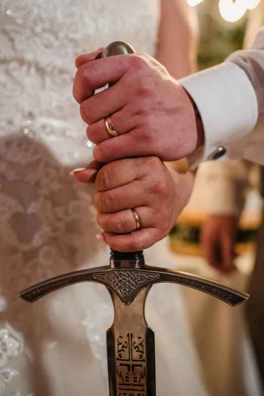 A bride and groom holding a sword.