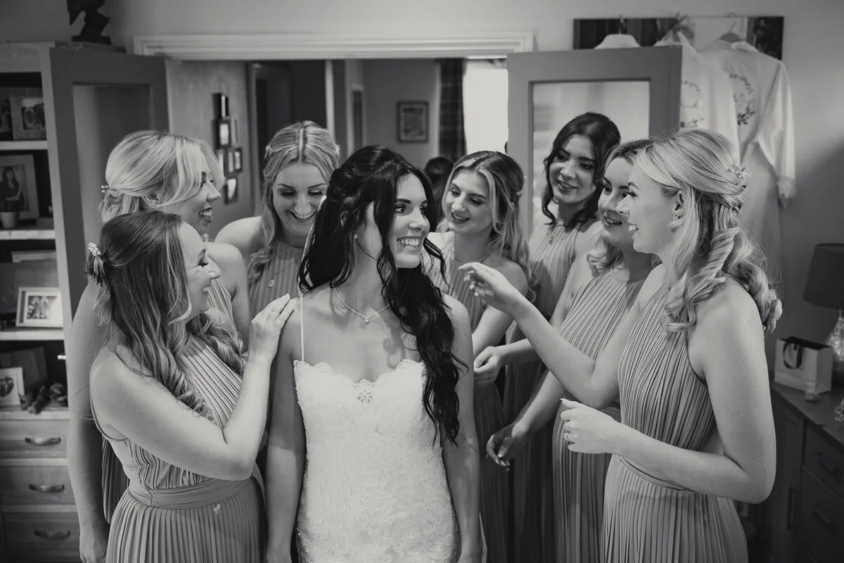 A bride and her bridesmaids look at each other in a mirror.