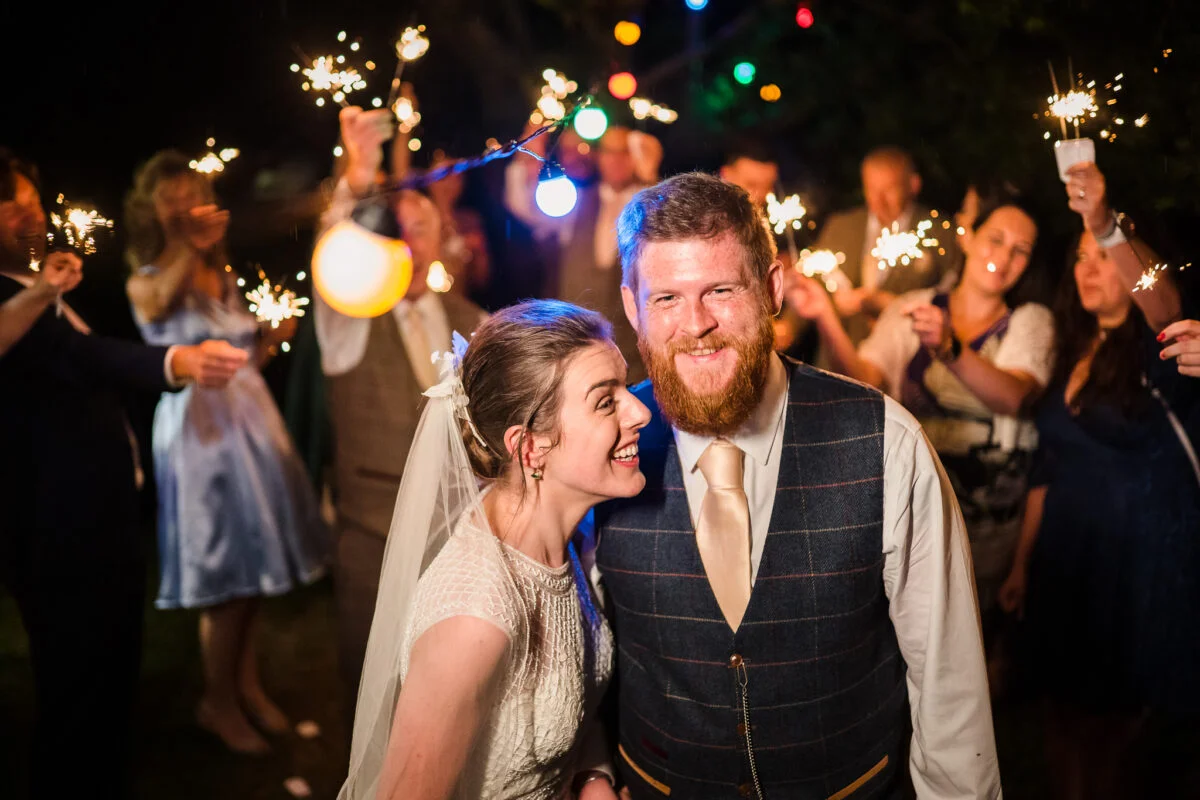 A bride and groom with sparklers in their hands.