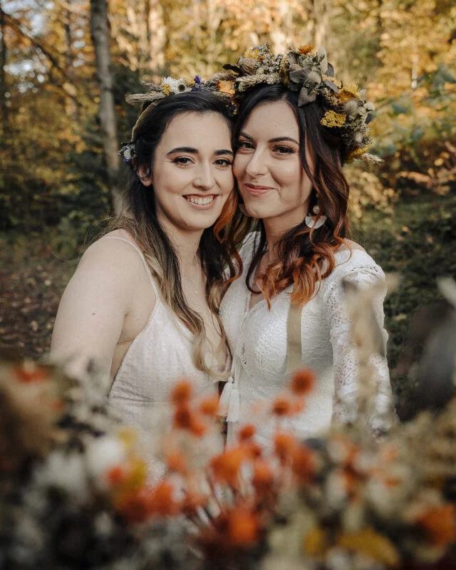 Two brides posing for a photo in the woods.