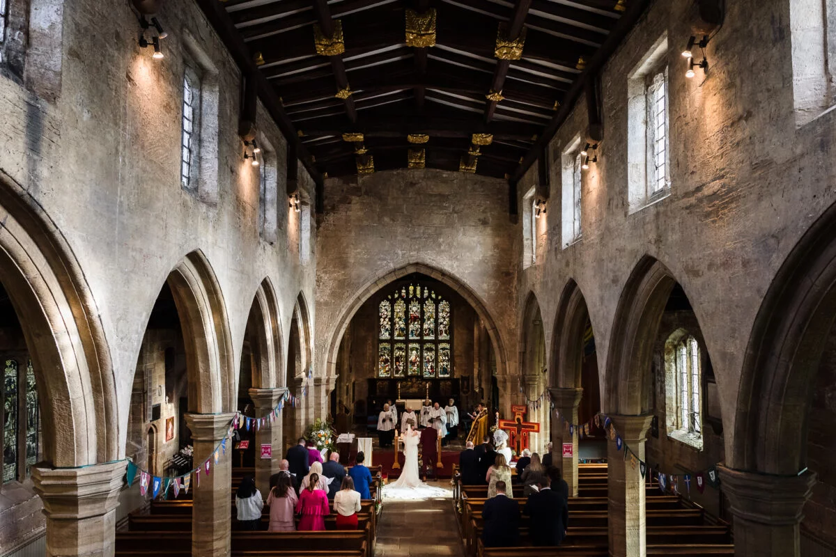 A wedding ceremony in a church with people standing in the aisle.