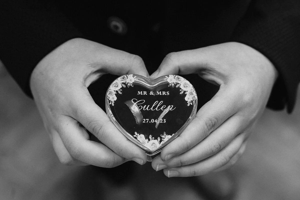 A black and white photo of a couple holding a heart shaped box.