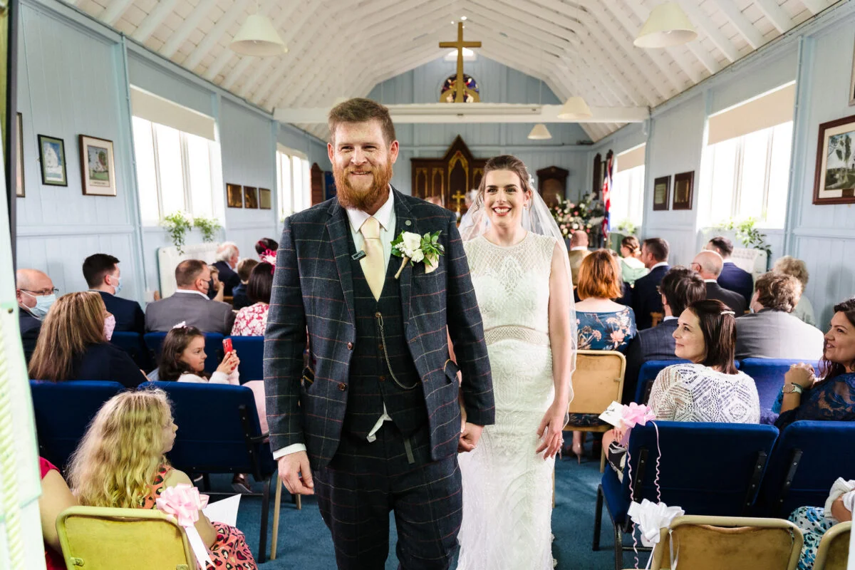 A bride and groom walking down the aisle of a church.