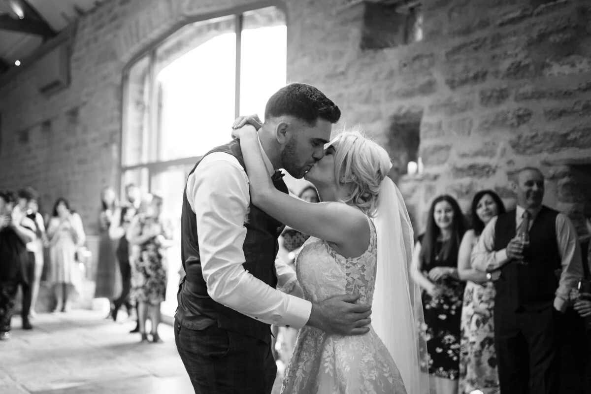 A bride and groom sharing their first dance in a barn.