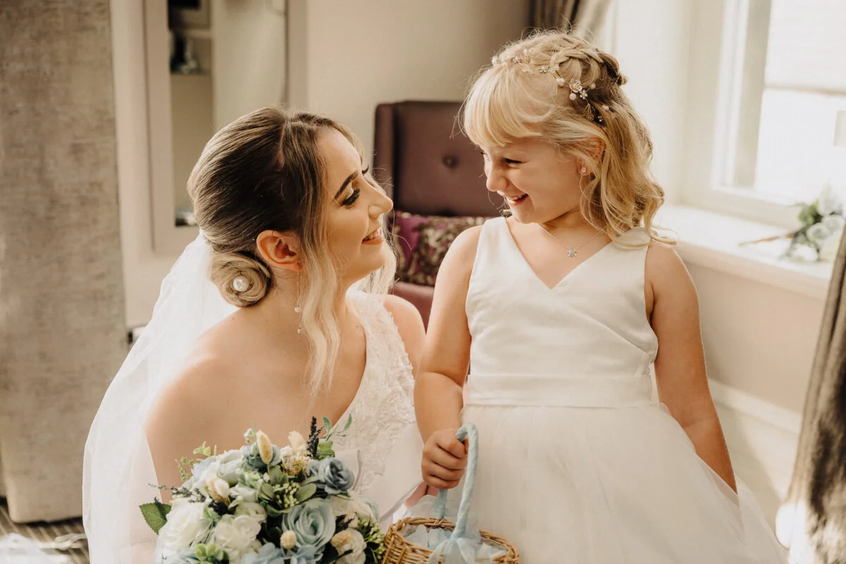 A little girl in a wedding dress with a flower in her hair.