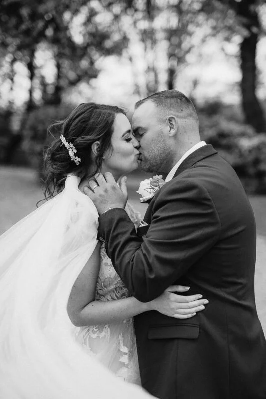 Black and white photo of a bride and groom kissing.
