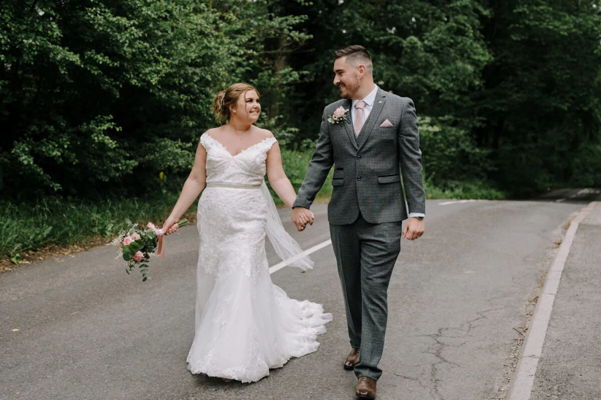 A bride and groom walking down a country road.
