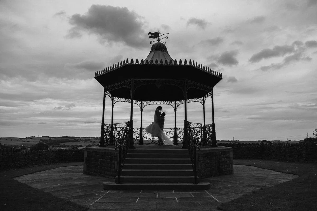 A bride and groom standing in front of a gazebo.