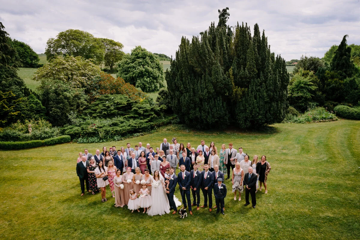 A group of wedding party posing for a photo in a garden.