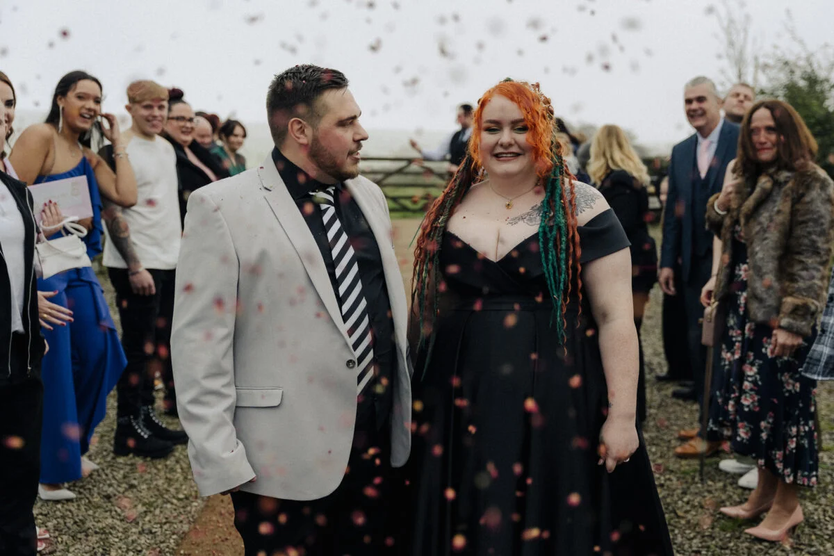 A bride and groom standing in front of confetti.