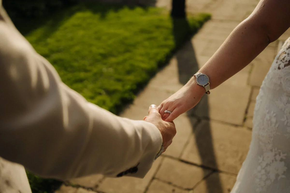 A bride and groom holding hands on a path.
