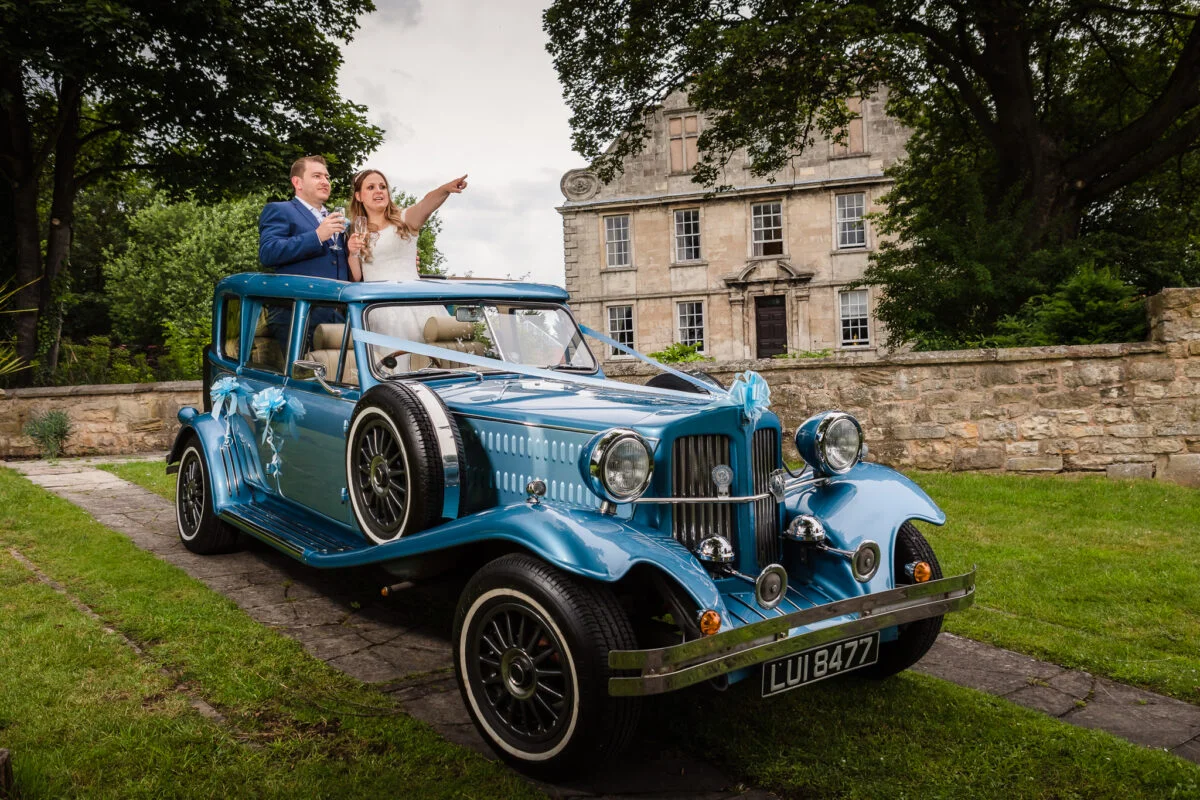 A bride and groom in a blue vintage car.