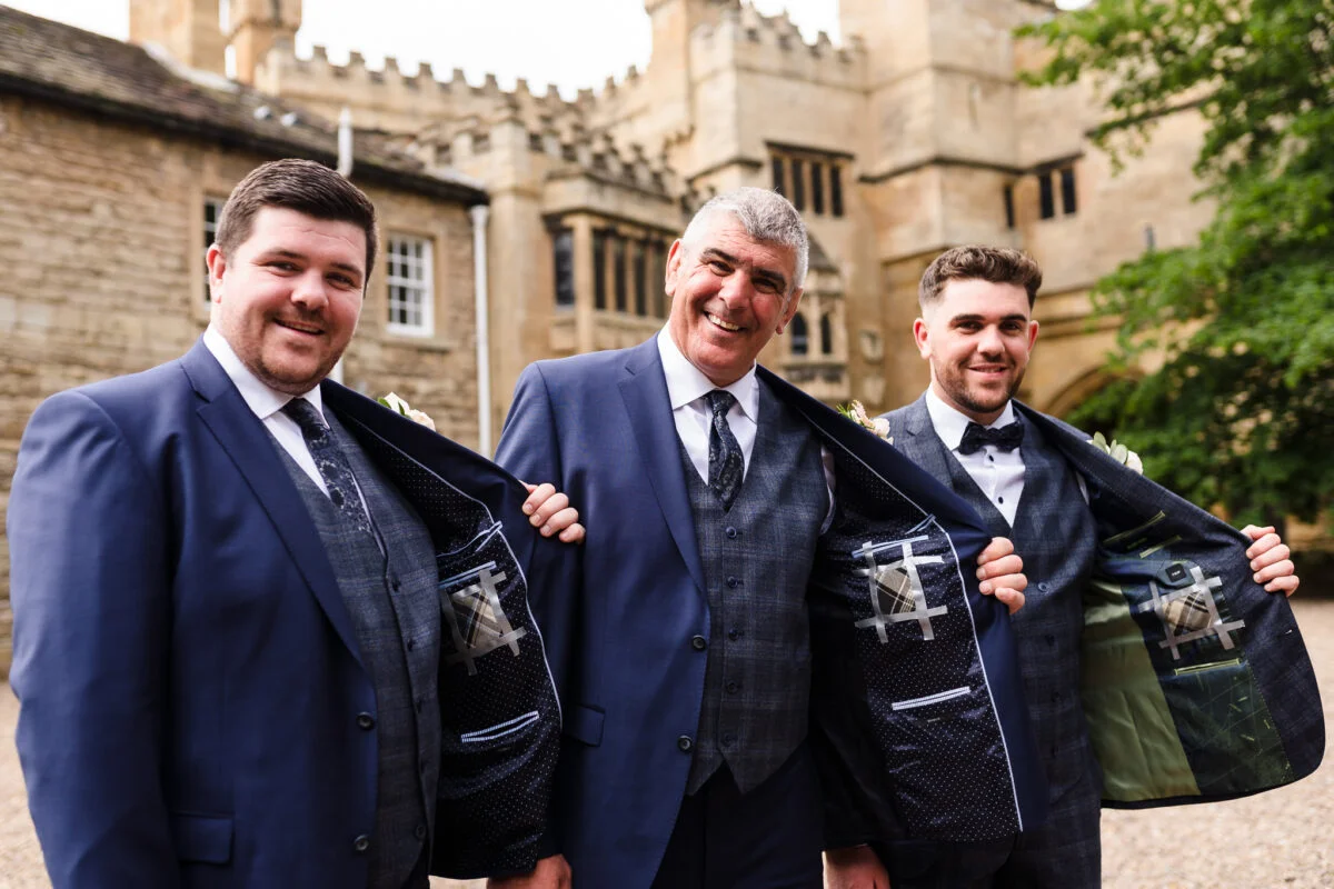 Three men in suits standing in front of a castle.