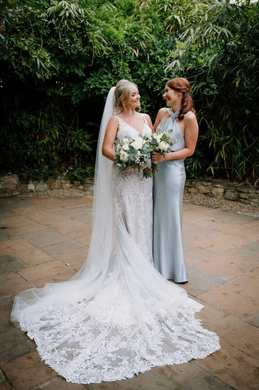 Two bridesmaids standing next to each other in a garden.